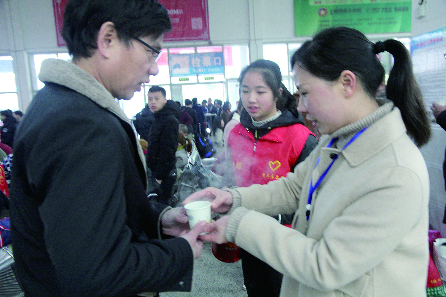 母女服務(wù)春運(yùn) 2月13日，記者在新邵分公司汽車站看到，該分公司安全科副科長李喜梅與其在新邵一中初中部1701班就讀女兒劉嘉怡在車站擔(dān)當(dāng)志愿者。李喜梅在候車室耐心為旅客釋疑解惑，劉嘉怡為旅客遞上一杯杯熱茶，有時(shí)母女也相互合作，其樂融融。 祖冠 攝影報(bào)道